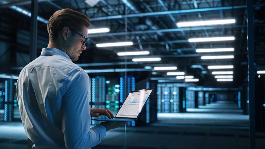 8 consigli per ricostruire una strategia dati pronta per l’AI Back View of Male Specialist Using Laptop in Big Data Center Office