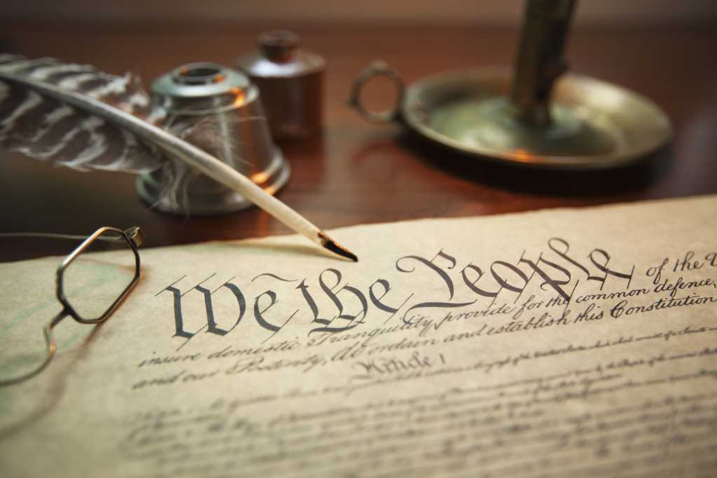 Why your 2026 IT strategy needs an agentic constitution Selective focus image of the United States Constitution with quill pen, glasses and candle holder