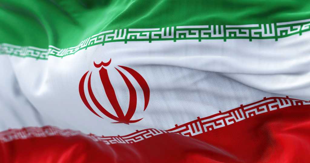Iran war set to hit global IT spending, IDC warns Close-up view of the Iran national flag waving in the wind. The Islamic Republic of Iran is a State of Asia located at the eastern end of the Middle East. Fabric textured background. Selective focus