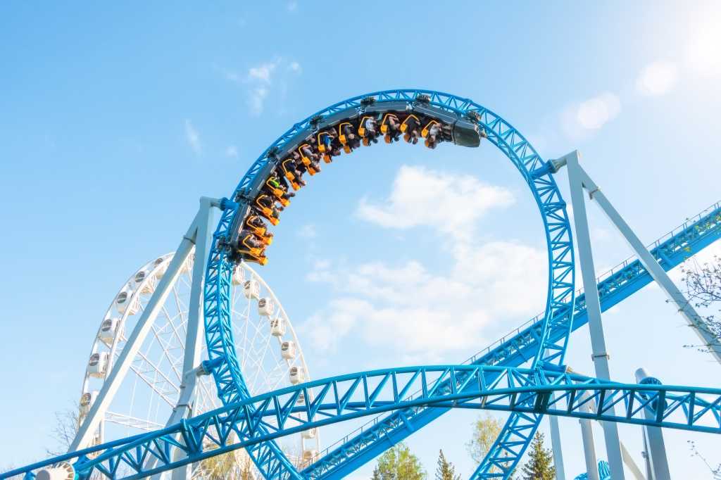 Shipping enterprise-quality code with AI agents upside down roller coaster in a loop against a cloud and blue sky amusement park
