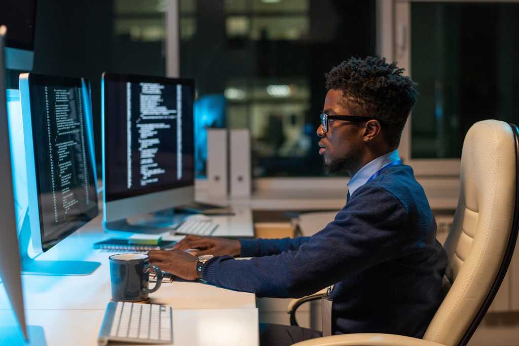 Using Visual Studio Code’s ‘air-gapped’ AI model mode Young it-engineer working with coded data while sitting in armchair in front of computer in office