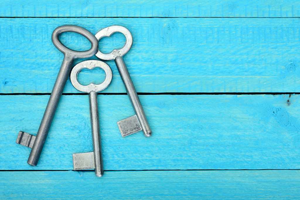Three keys to deploying AI agents Top view of three 3 keys on a wooden blue table